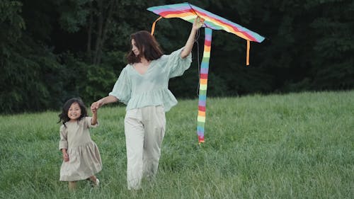 Mother and daughter walking in Park with a Big Kite in Hand