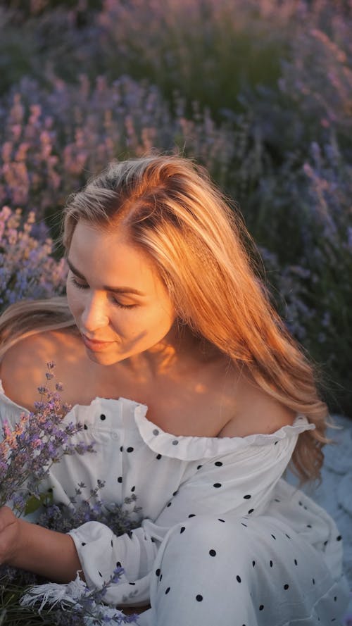 Woman in Polka Dots Dress Smelling the Lavender Flowers