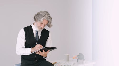 Elderly Man Thinking Deeply while Writing on Paper