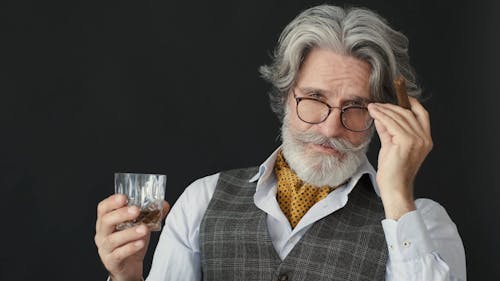 Man Holding a Glass of Whiskey and a Tobacco