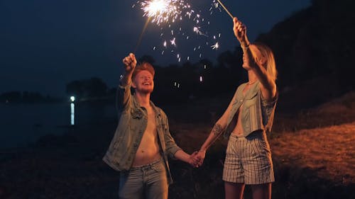 A Couple Holding Two Lighted Sparklers