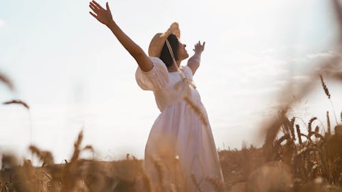 Woman in White Dress and Hat Dancing in Wheat Fields