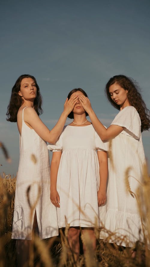 Two Girls Closing Eyes of One of their Friend