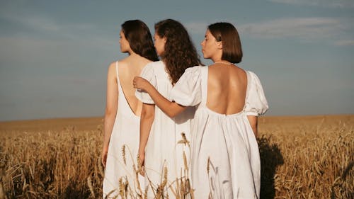 Women in White Dresses Standing in Wheat Field