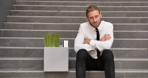 Sad Office Employee Sitting on Stairs after getting Fired from his Job