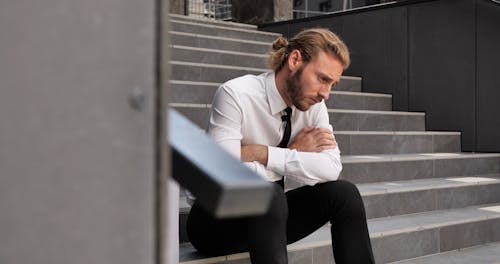 Fired Frustrated Man in Suit Sitting at Stairs with Belongings