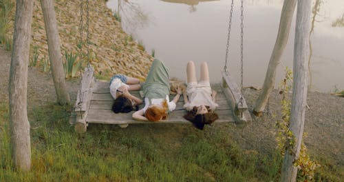 Mother and Daughters Lying on a Wooden Swing