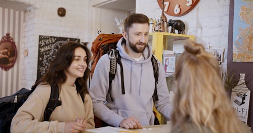 Two Travelers Talking to a Woman in Front Desk