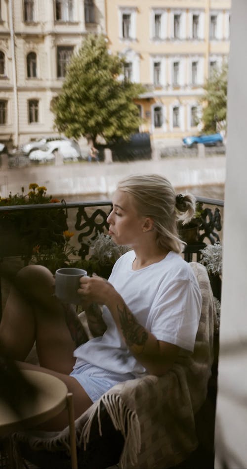 A Woman Having Coffee On A Veranda