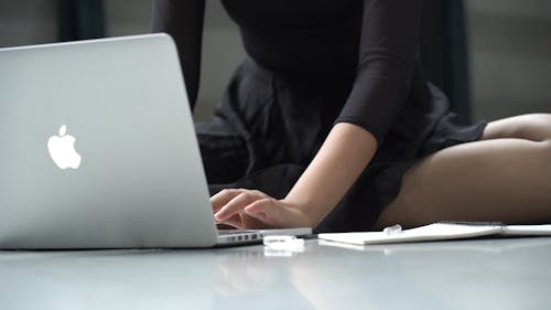 Person Using Her Laptop While Taking Down Notes