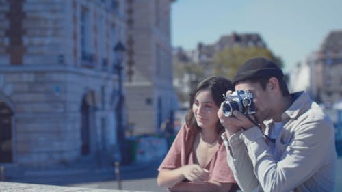 Man Taking a Photo Using His Camera While Standing Beside His Girlfriend