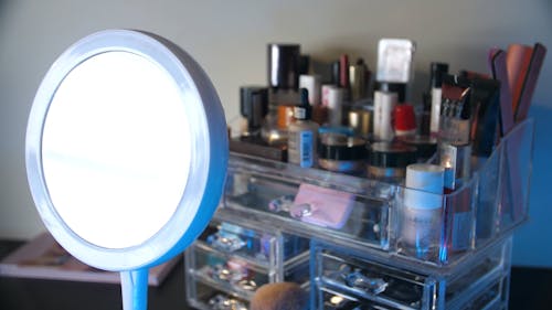 Close-Up View of a Round Mirror Glass Against Set of Cosmetic Products