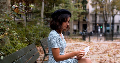 Woman Sitting on a Park Bench Reading a Book