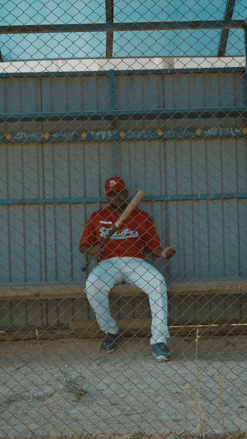 Baseball Player Walking Towards the Chain-Link Fence While Holding His Baseball Bat