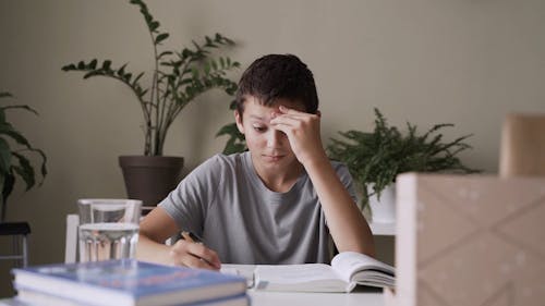 Boy Looking Tired While Self-studying at His Home