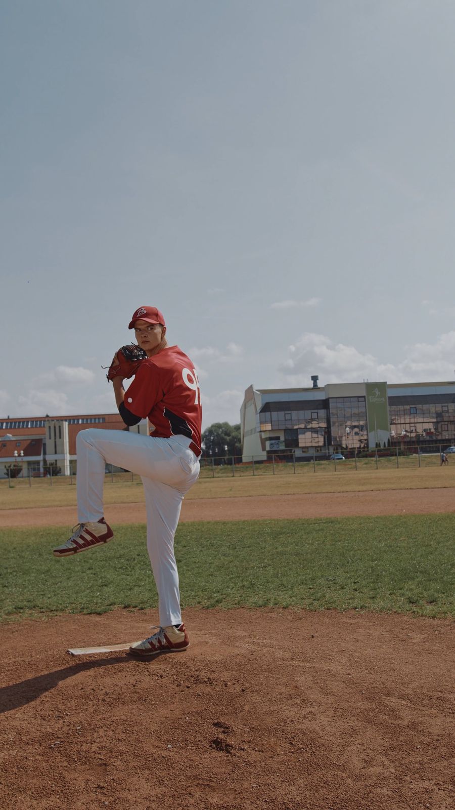 Baseball pitcher mid-throw on a sunny field