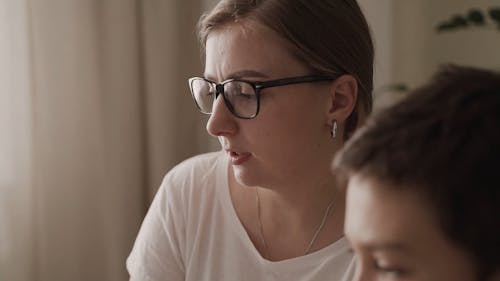 A  Woman Tutoring A Kid At His Home