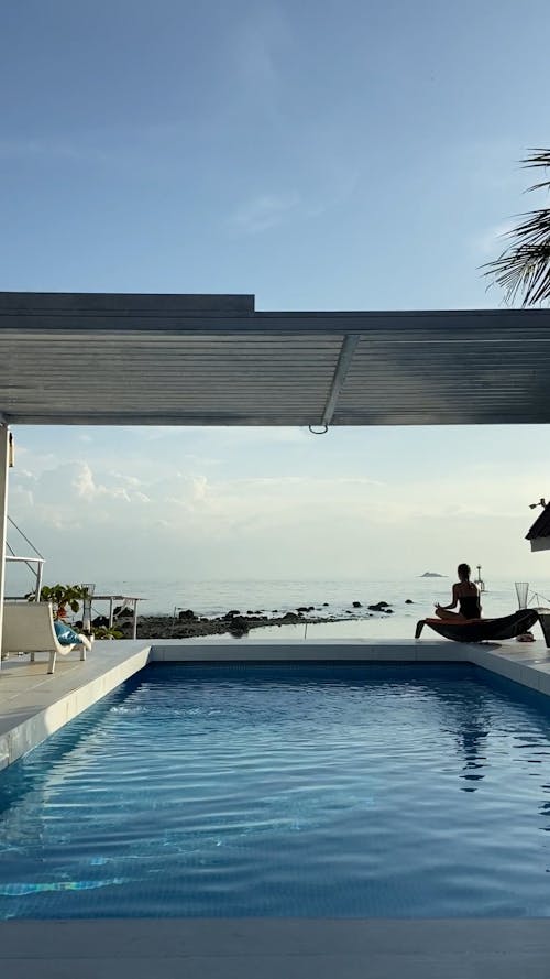 Wide Angle Shot of a Woman doing Yoga by the Swimming Pool