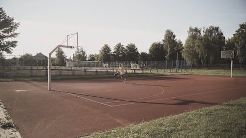 Man Playing Basketball in a Basketball Court