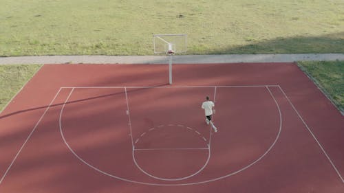 A Man Shooting A Basketball By A Reverse Layup