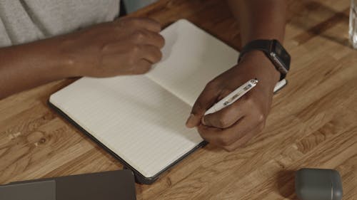 Man Writing with his Left Hand in a Notepad