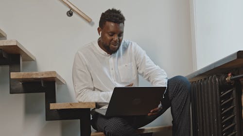 Man Sitting on Staircase and Attending Video Conference 