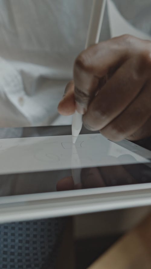 A Person Drawing On A Tablet Using A Stylus Pen