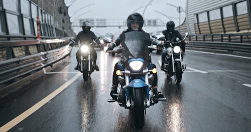 A Group Of Bikers Riding On Wet Road