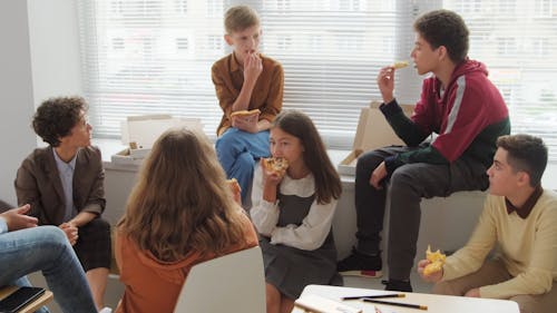 Students Eating Their Pizza While Talking to Their Teacher