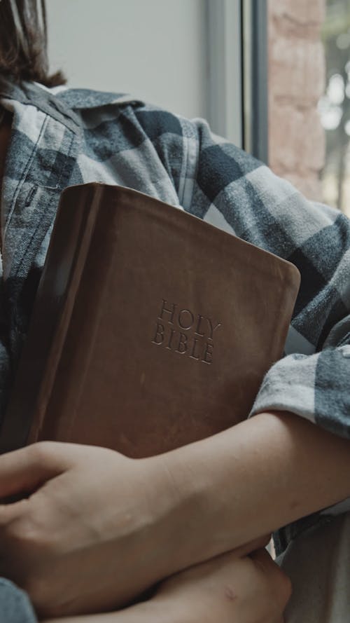 Woman Holding a Bible While Looking Pensive