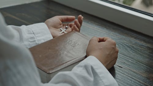 A Person Holding Cross and Holy Bible