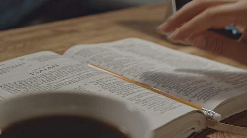 Close-Up View of Person Picking Up the Pencil and Write on the Bible