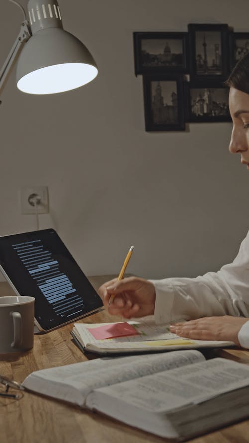Woman in White Dress Shirt Using Her Ipad While Writing