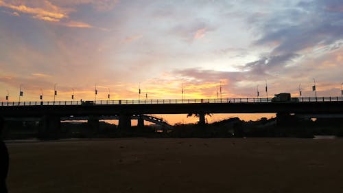Silhouette of Vehicles Driving on a Bridge During Golden Hour