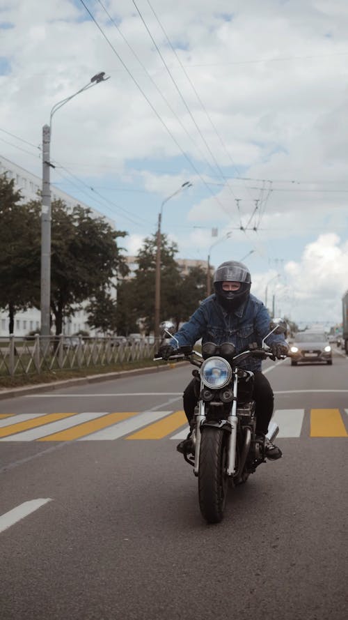 Man in Blue Denim Jacket Driving His Motorcycle on Road