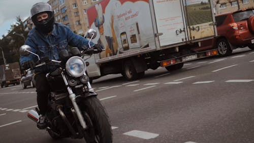 Man in Denim Jacket Riding His Motorcycle on Road