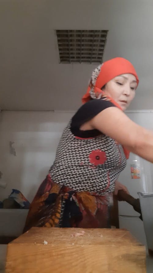 Woman Chopping a Raw Chicken Using an Axe