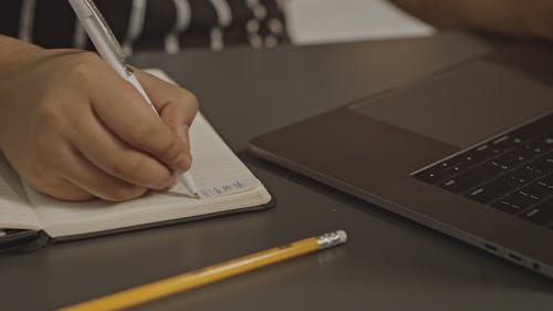 Man Writing on His Notebook