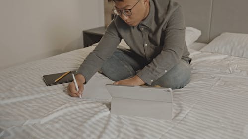 A Man Writing In His Bedroom