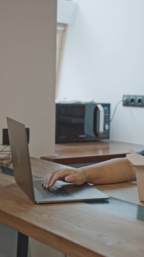 A Man Using His Laptop while Eating Noodles