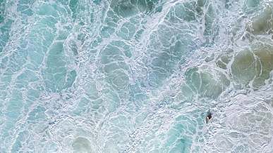 aerial footage of person swimming on the sea