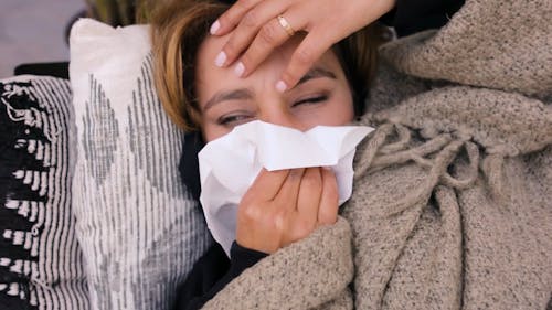 Woman Under Flu Cleaning her Nose with Tissue