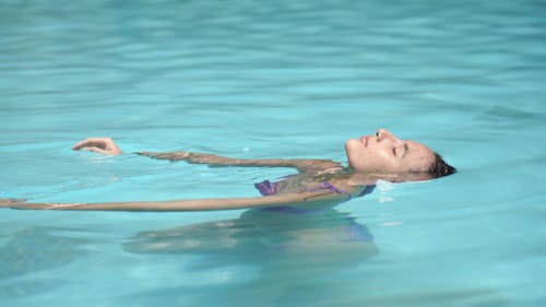 紫色比基尼在游泳池里游泳的女人