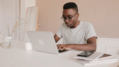 Side View of a Man Working on his Laptop at his Work Desk