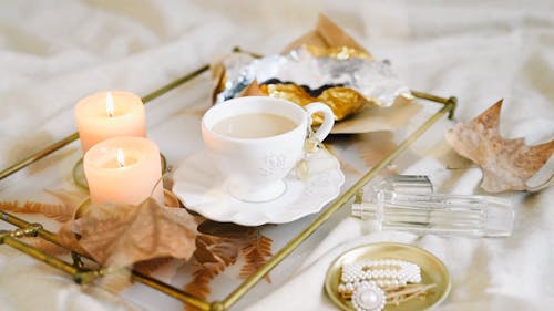 A Cup of Tea Placed on a Table with Candles and Chocolates