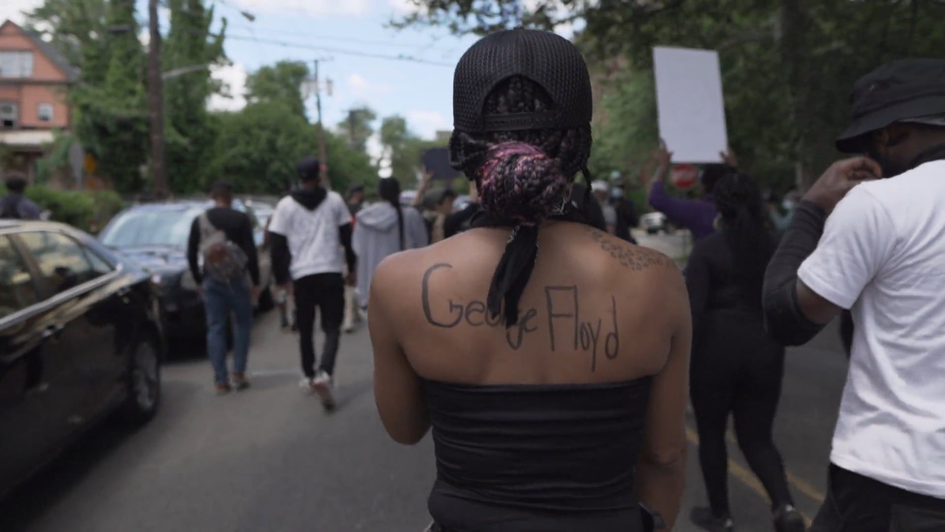 Woman Walking in BLM Protest with George Floyd written on her Back Free ...