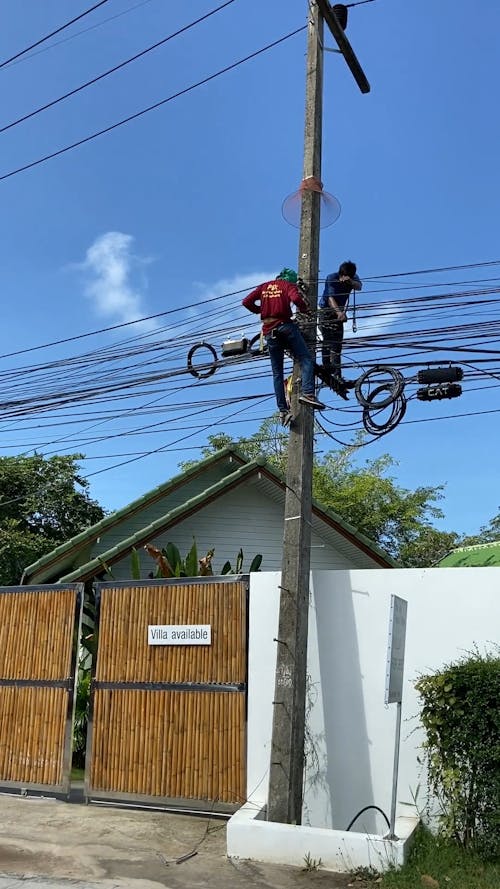 Two Men On The The Electric Post Fixing Cable Wires