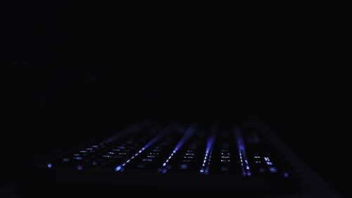 A Person Typing on a Keyboard in the Dark