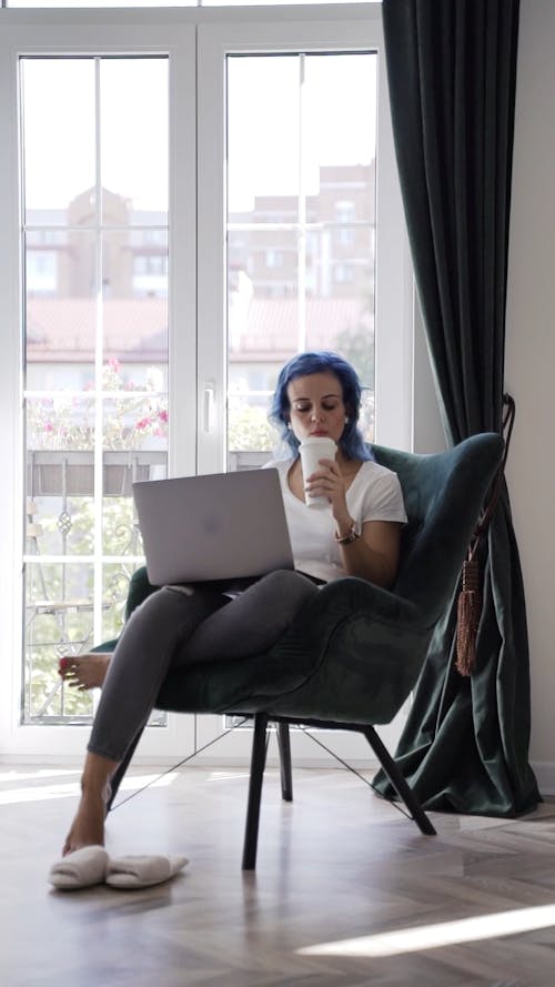 Woman Using a Laptop Then Drinking Coffee