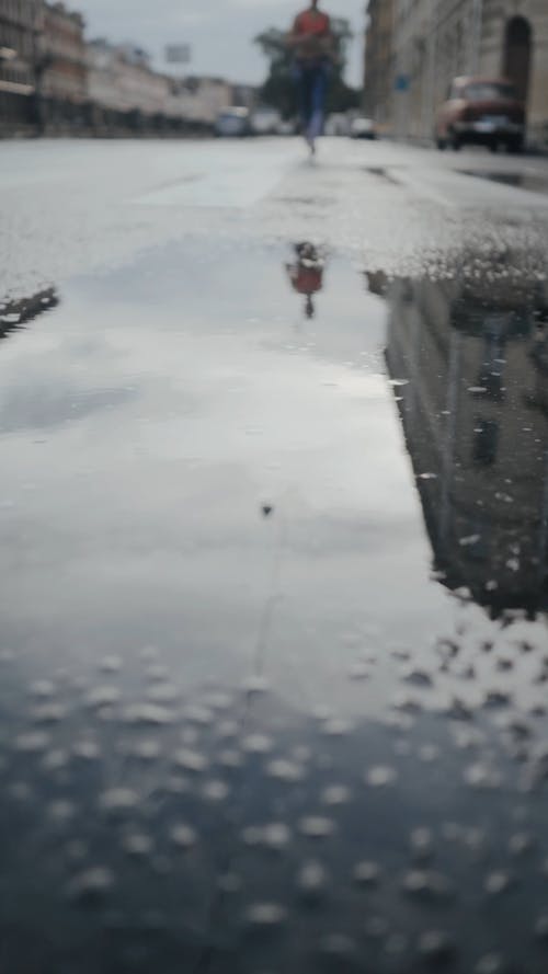 Person Jogging Through Puddles on the Street